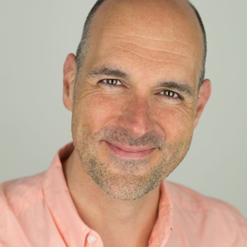 Headshot of James McLean. He is bald with a neatly trimmed beard and is wearing a light peach shirt. James is smiling warmly and looking directly at the camera, giving a friendly and approachable expression. 