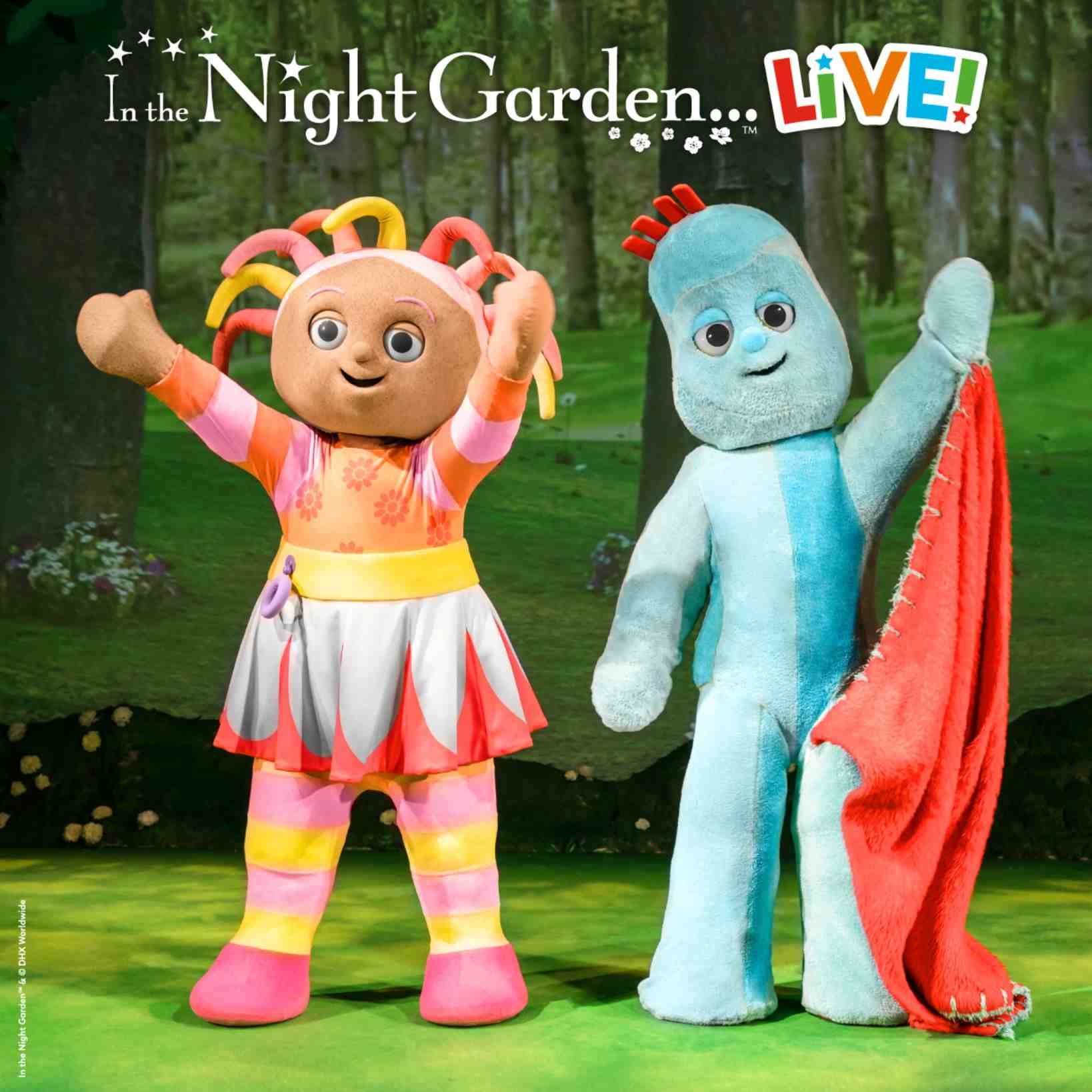 Upsy Daisy and Igglepiggle from In the Night Garden… LIVE! stand on stage in a woodland setting, smiling and waving at the audience