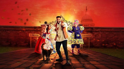 Promotional poster for the pantomime 'Dick Whittington' featuring three characters: Dick Whittington in the centre, a woman in a colourful dress on the left, and a character in a traditional British Pantomime Dame costume on the right. A cat stands in the foreground. The background includes signs pointing to 'London' and 'Huddersfield' with the dome of St. Paul's Cathedral visible.