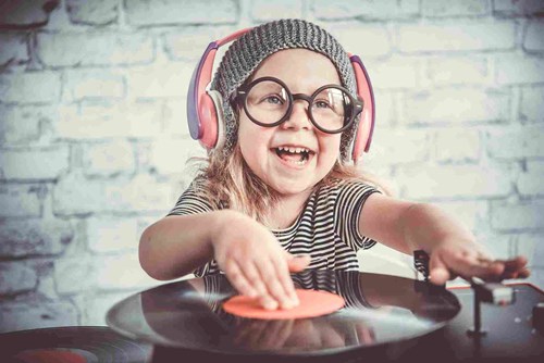 Young child wearing headphones playing with a record player. 