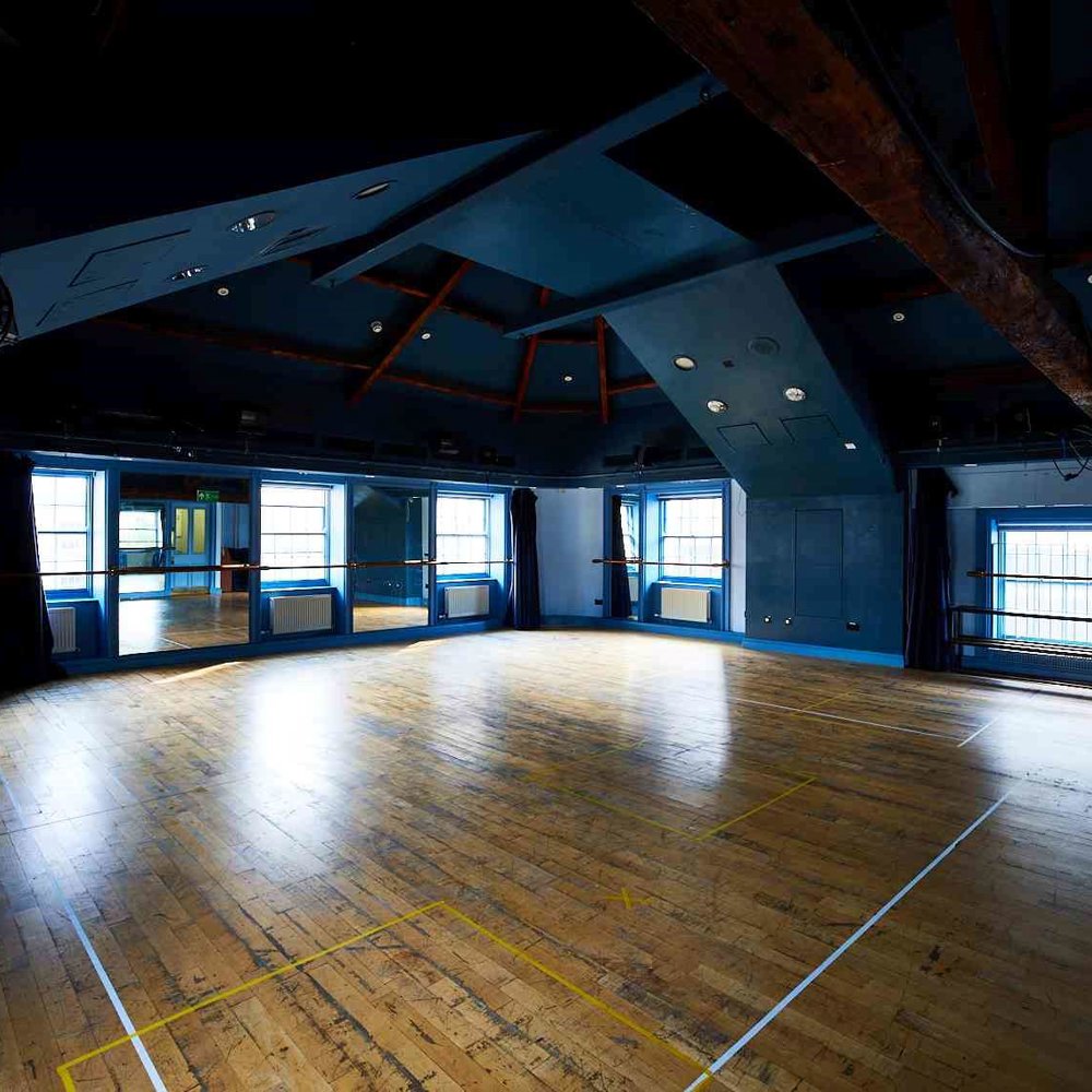 Our Attic Theatre, a large room with blue walls and wooden floor with lots of natural light. An ideal space for rehearsals and workshops.