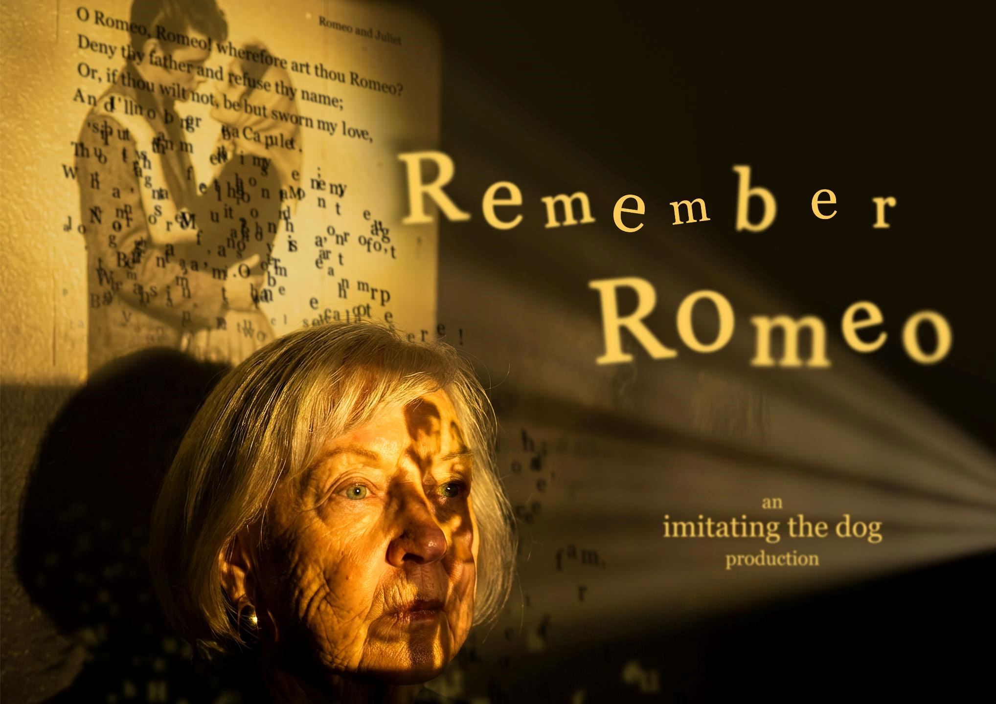 Promotional image for Remember Romeo. An older woman with silver hair is illuminated by warm golden light as projected text and images from Romeo and Juliet fall across her face and the wall behind her. The shadow of a young figure appears over a page of Shakespeare's text, while the title "Remember Romeo" is projected prominently to the right.