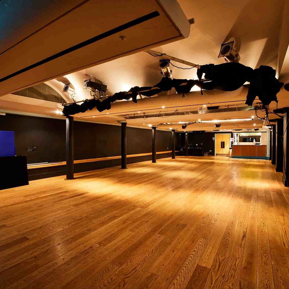 The Lawrence Batley theatre's Cellar Theatre. A large space with wooden floors and painted black walls with a lighting rig on the ceiling. 